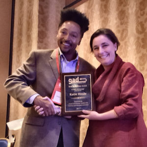 Photo of winner receiving prize plague from awards committee chair.